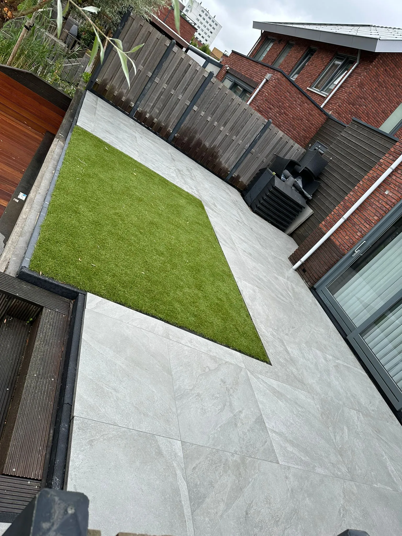 Betegelde achtertuin met houten schutting