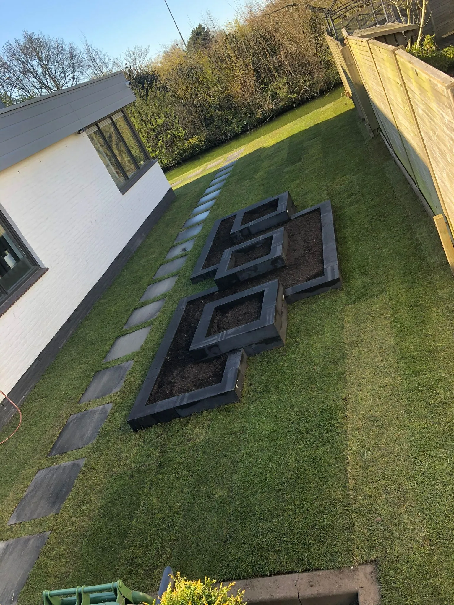 Aangelegde tuin met gras, stapstenen en plantenbakken